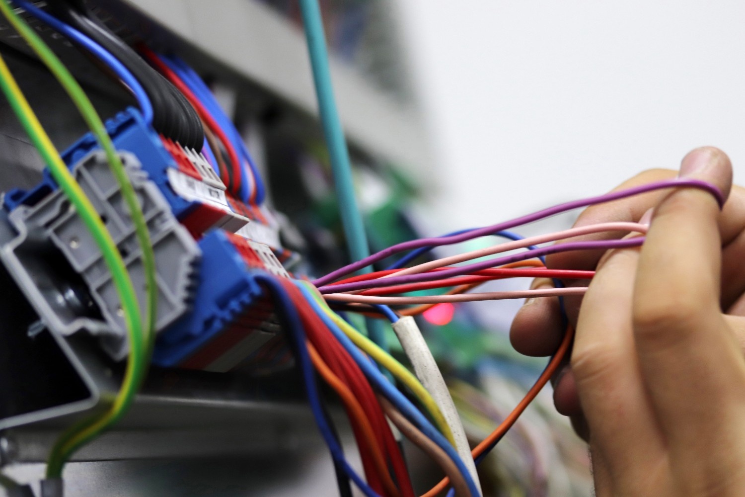 Electrician organizing color-coded wire connections for a clean, code-compliant electrical panel install.
