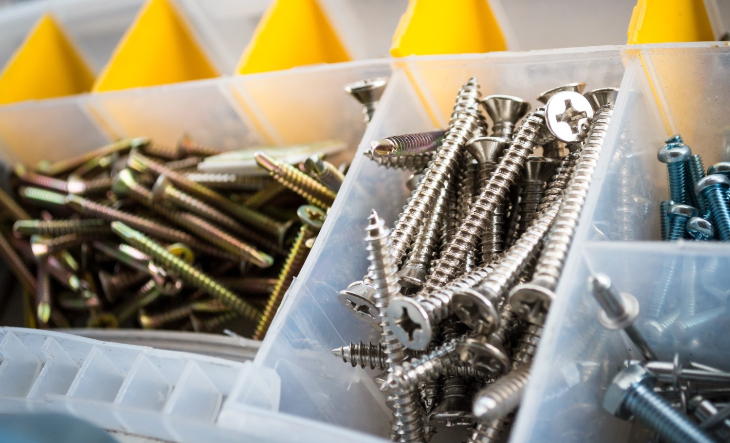 Assorted hardware screws and fasteners organized in a plastic storage box for jobsite or workshop use.